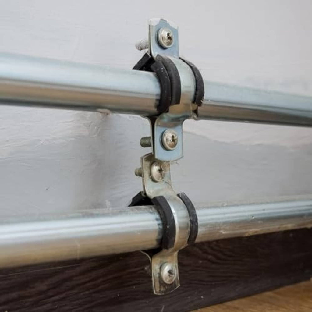 Black rubber split-ring clamp securing metal pipes with zinc bolts and brackets