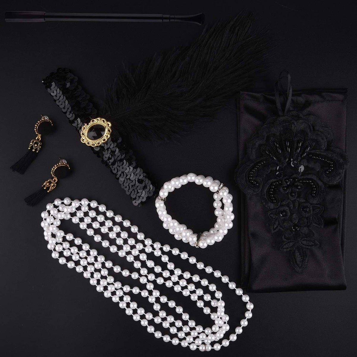 Flapper accessories flat lay: feather headband, pearl necklace strands, tassel earrings, gloves