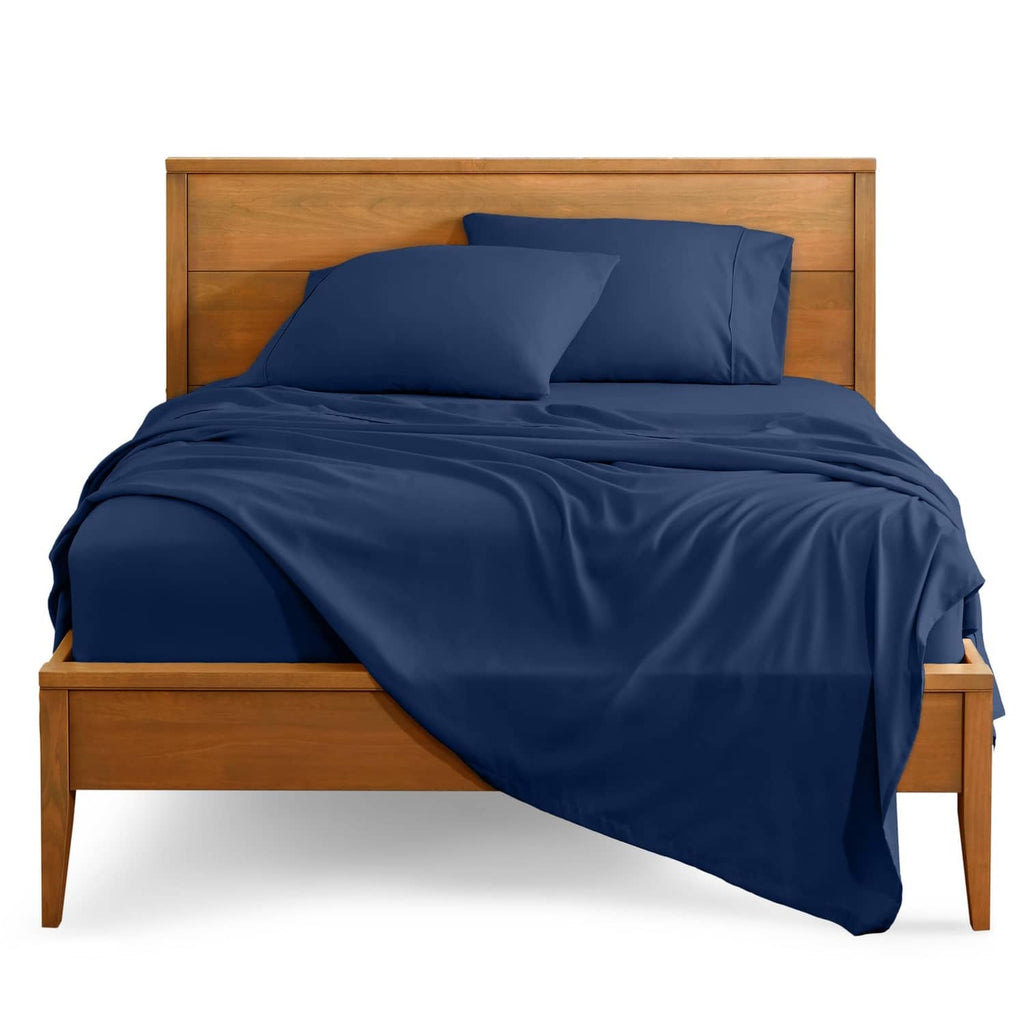 Dark blue full bed sheet set with fitted sheet and pillowcases on a wooden bed frame