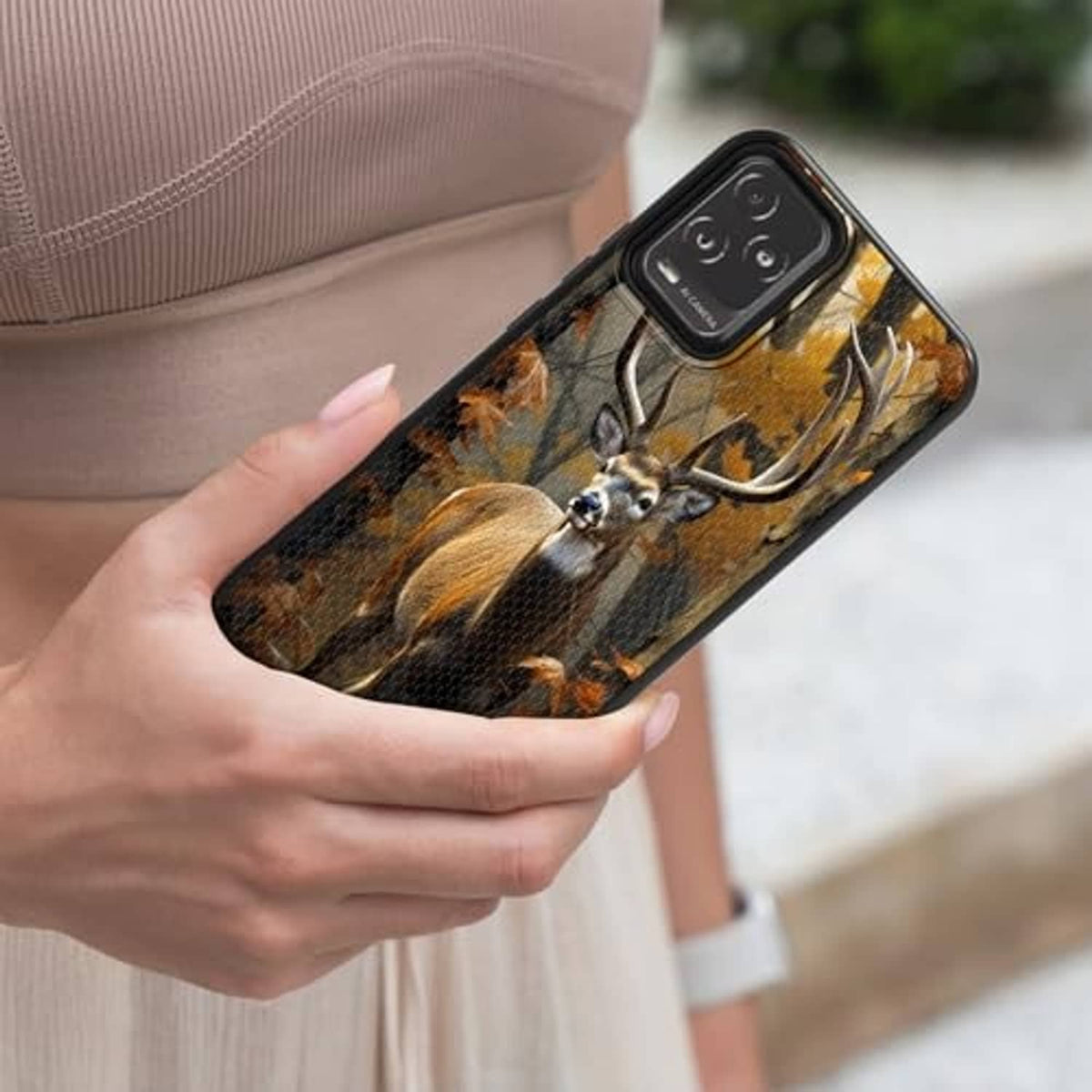 Deer camouflage rugged phone case in hand, black frame with raised camera guard.
