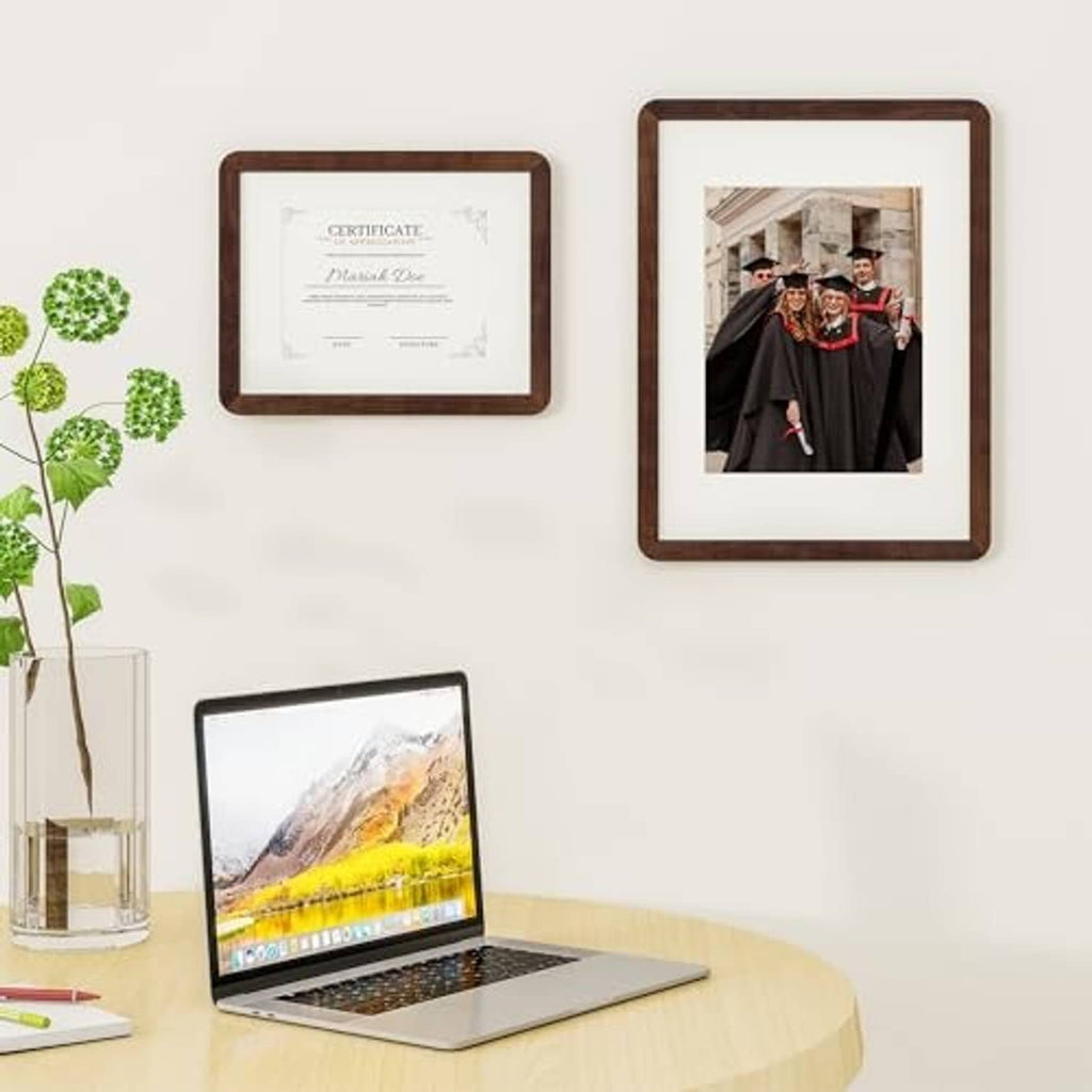 Set of dark walnut wood picture frames on wall with certificates and photos