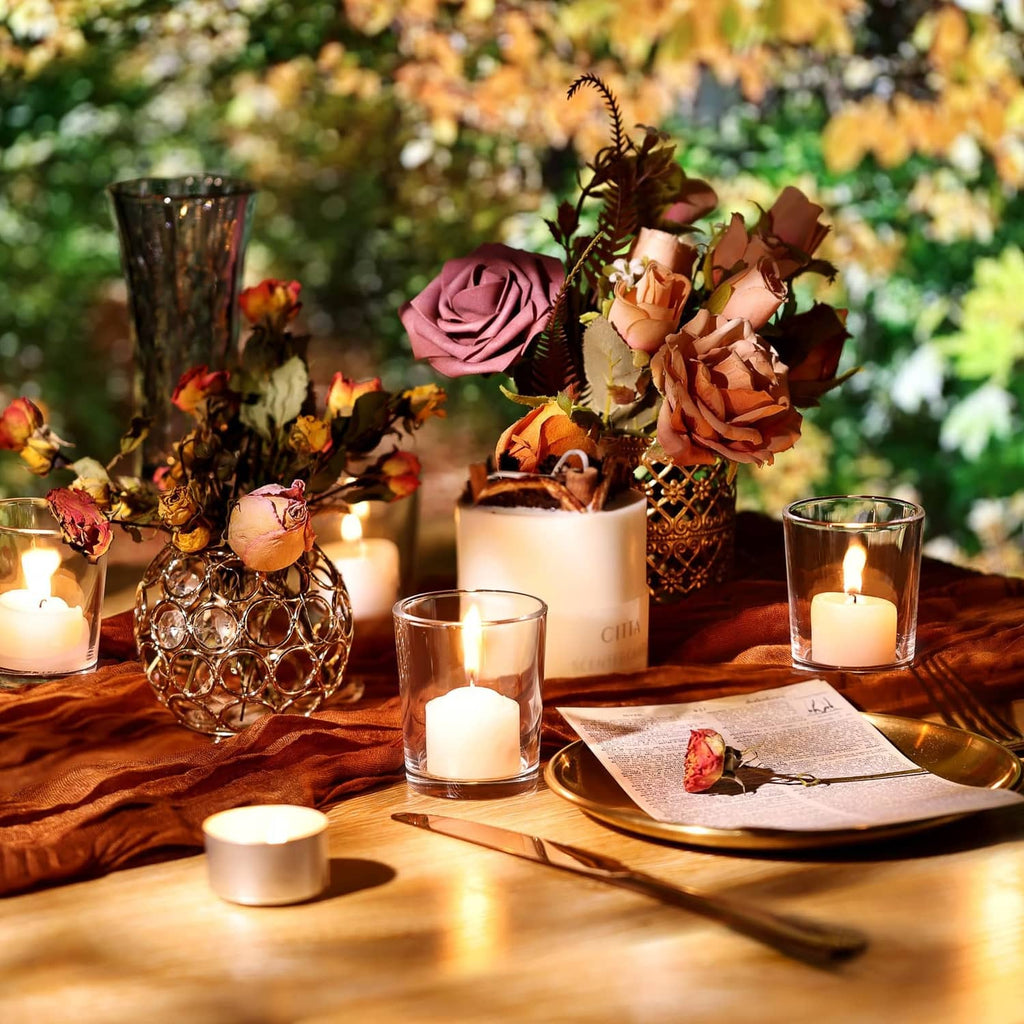 Clear glass tea light holders with lit candles on a wooden table