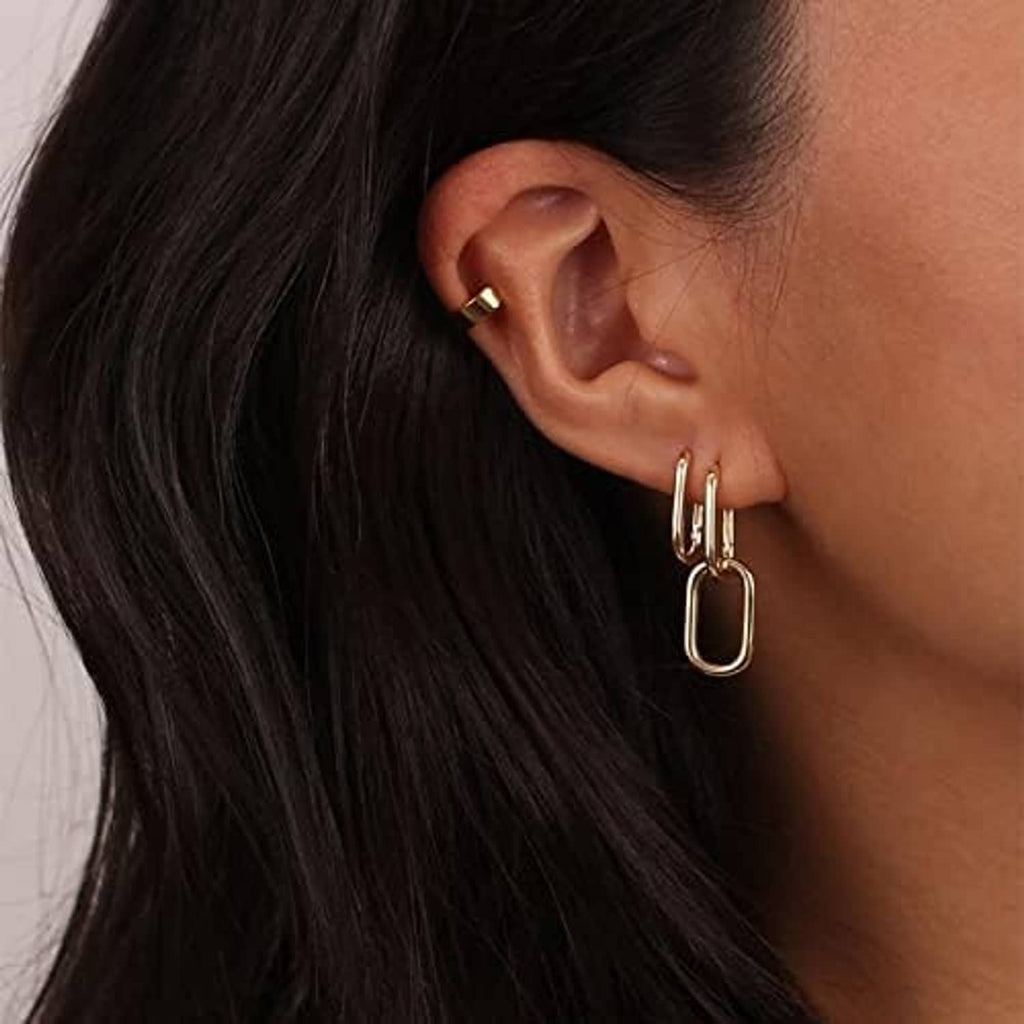 Gold paperclip huggie hoop earrings with rectangular loop, close-up on ear