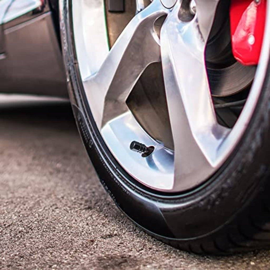Black tire valve cap installed on a car wheel valve stem
