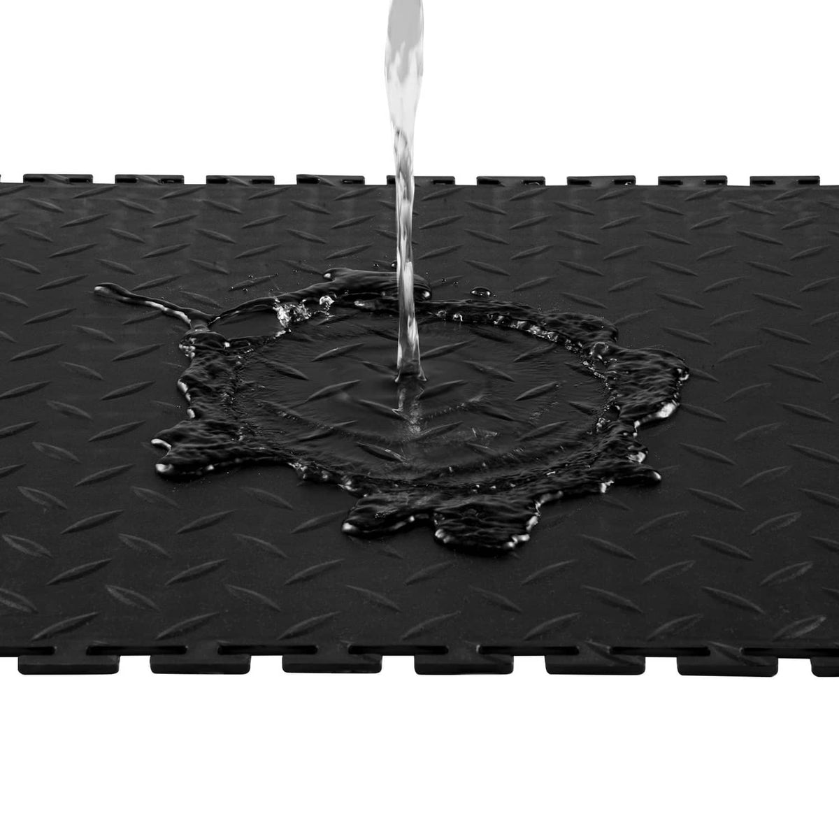 Black interlocking garage floor tile with raised diamond pattern; water pooled on surface