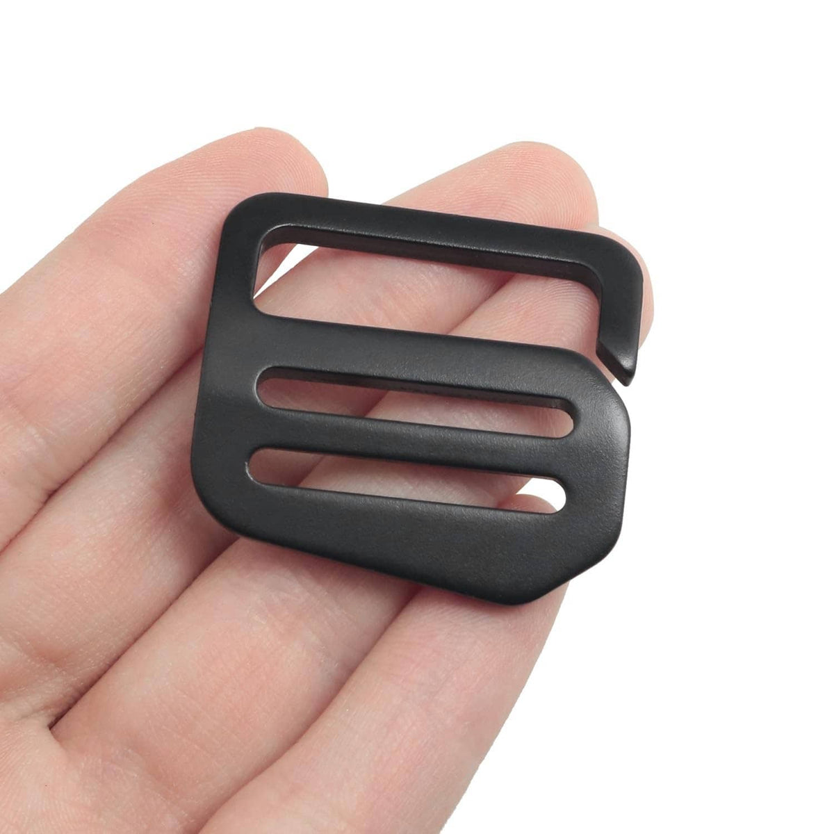 Black wave button buckle held in hand, showing rectangular slots