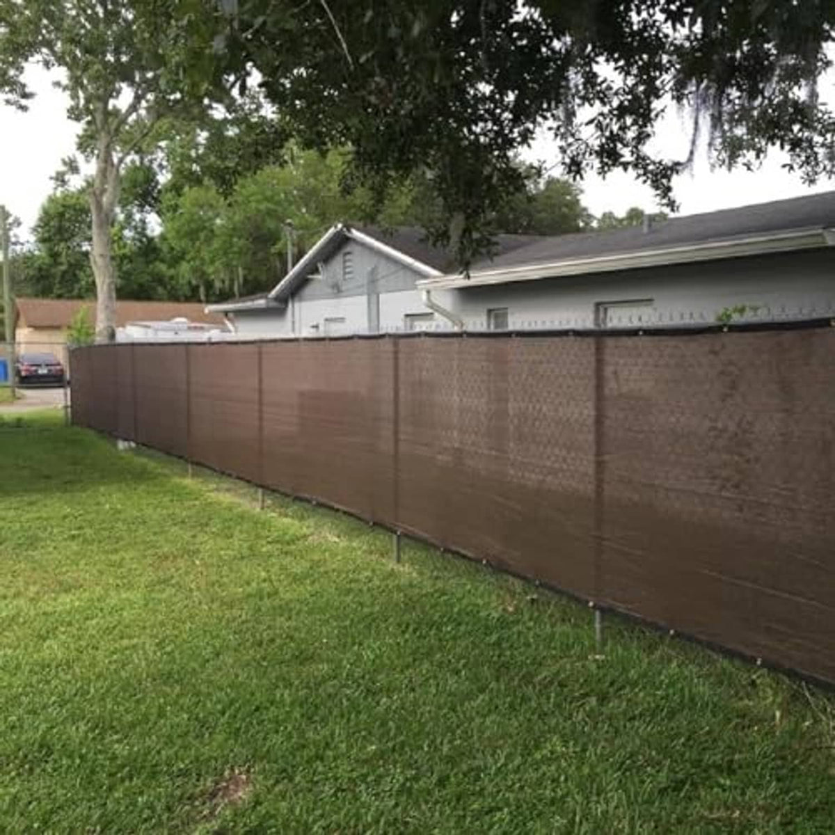Brown woven privacy screen fabric stretched along an outdoor fence