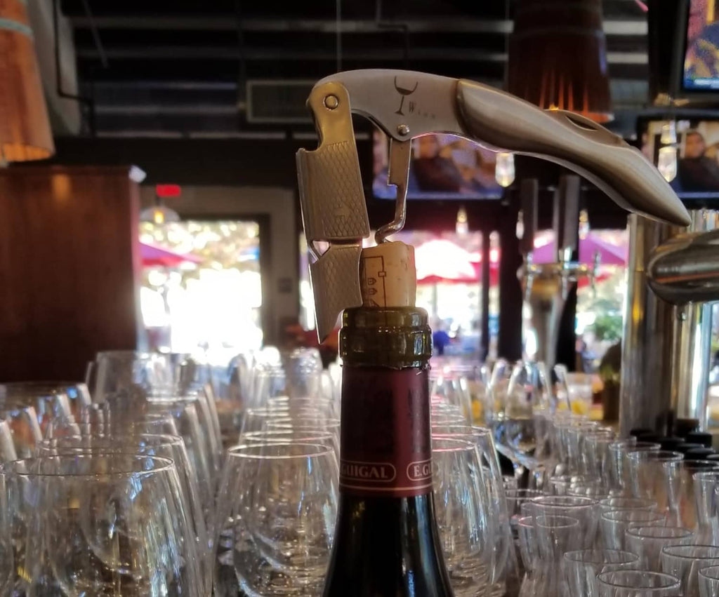 Stainless wine corkscrew held at a bottle, with grooved spiral and lever