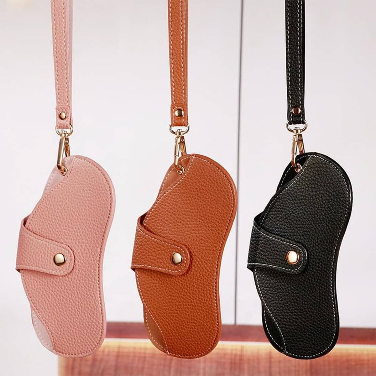 Soft leather sunglasses cases in pink, orange, and black with lanyard straps
