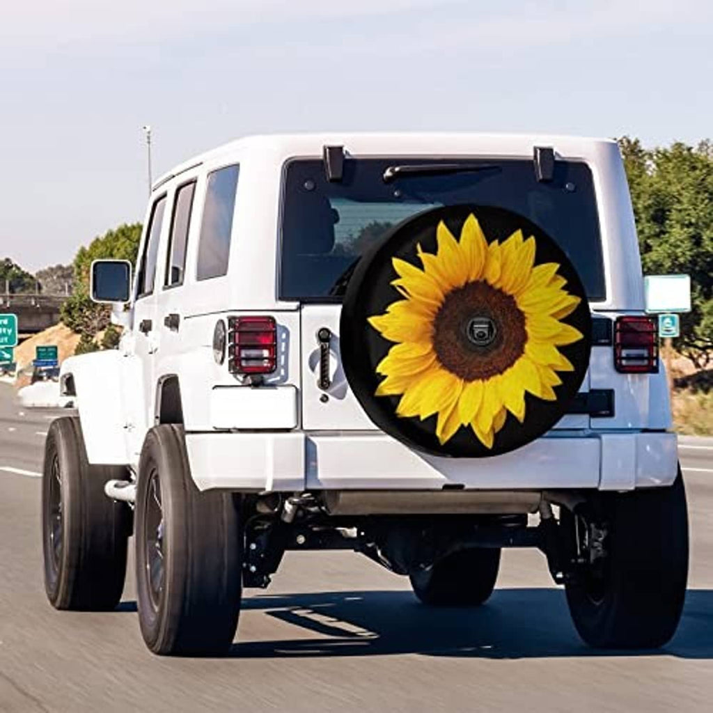 Black spare tire cover with sunflower graphic mounted on rear of white SUV, camera hole