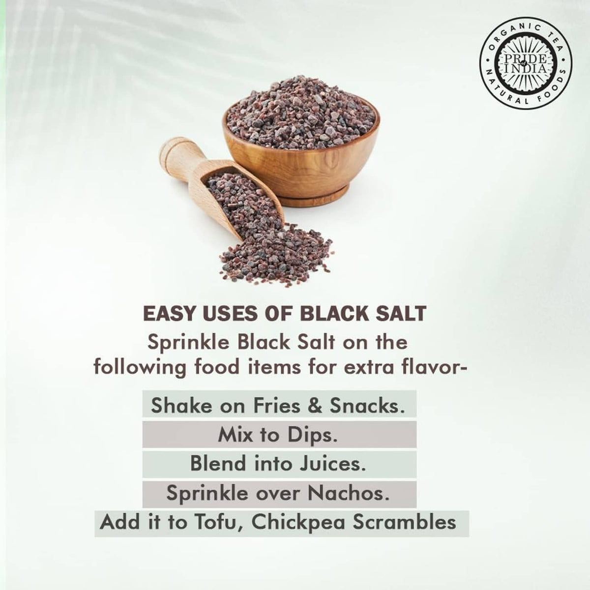 Coarse dark black salt crystals in two wooden bowls with a scattering pile