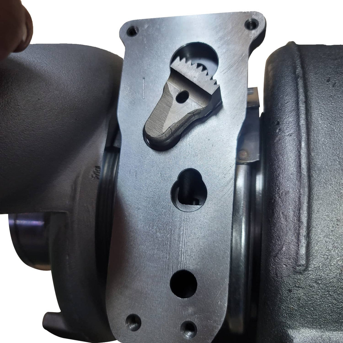 Turbocharger actuator bracket plate on cast housing, close-up