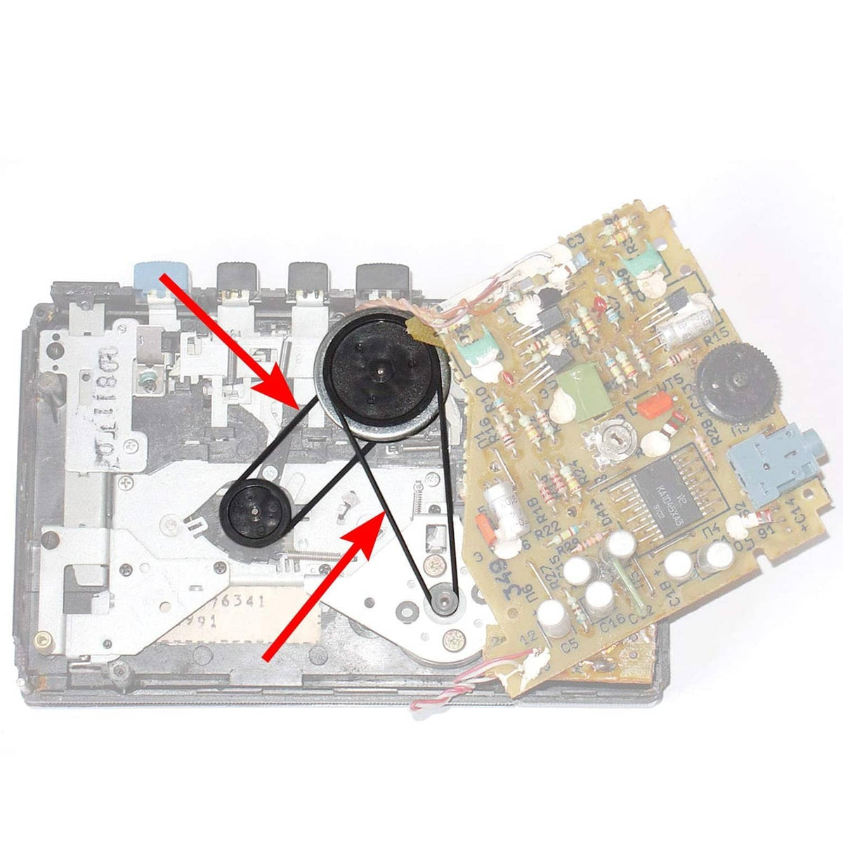 Opened cassette player drive system with thin black belts and internal components.