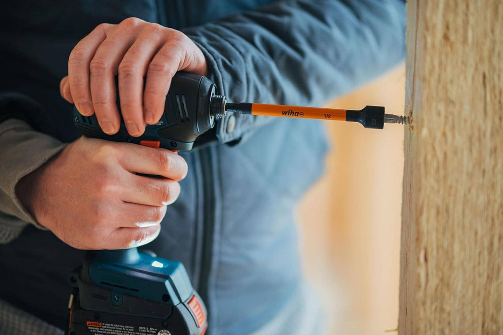 Orange magnetic nut setter bit in a drill during fastening, with black hex tip