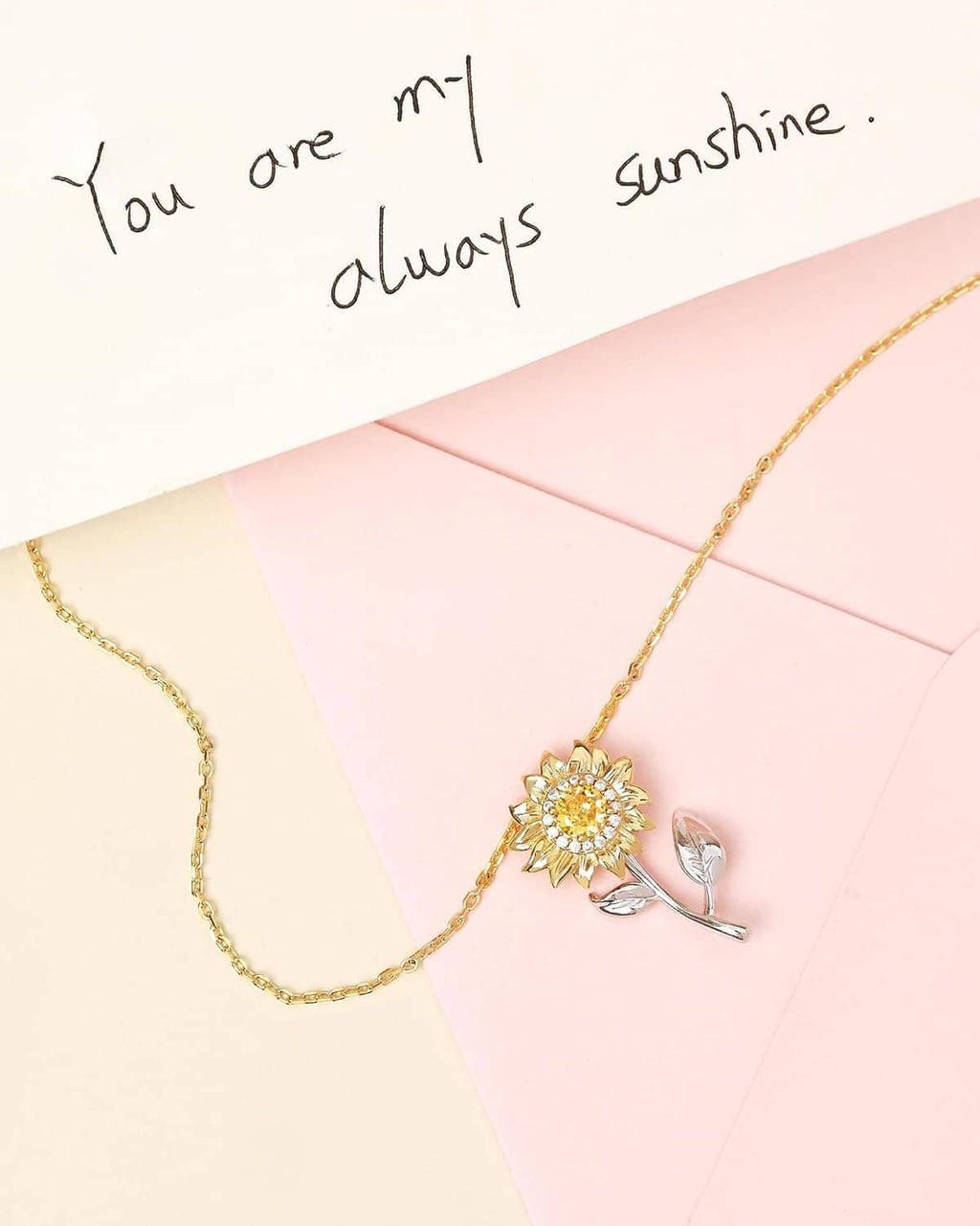 Gold-tone chain necklace with sunflower pendant and leaf-shaped spinner charm