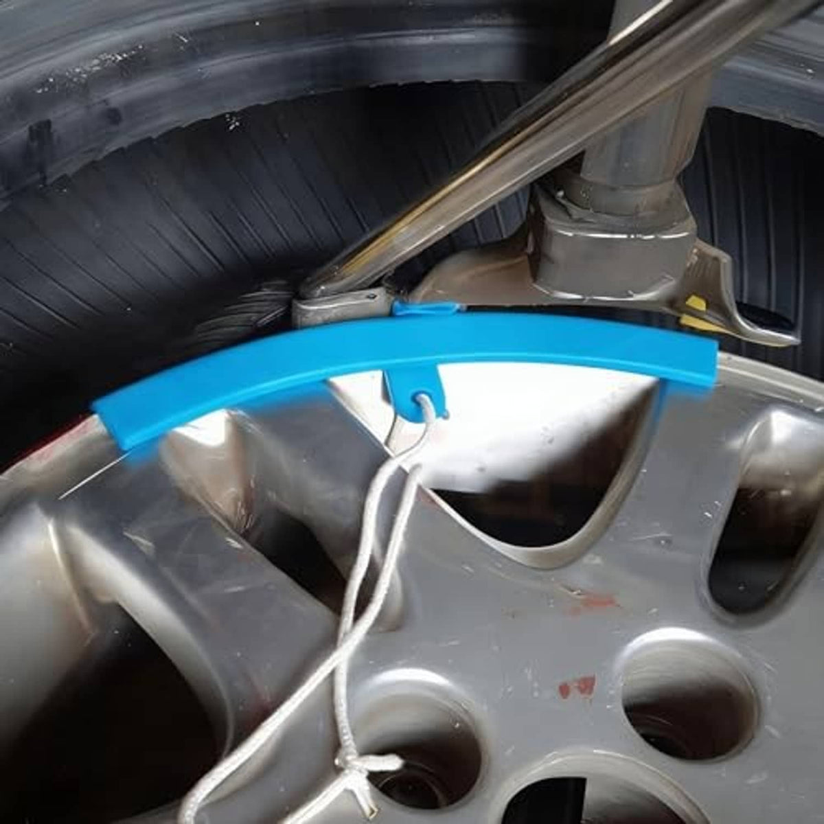 Blue rim protector sleeve fitted on wheel rim inside tire-changing setup
