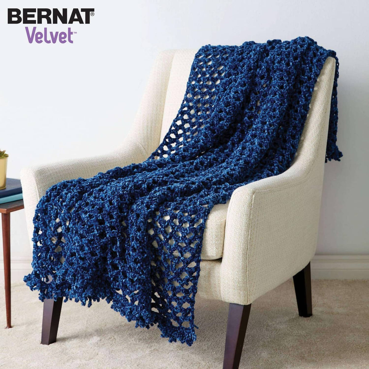 Blue knitted afghan draped over armchair, chunky textured loops
