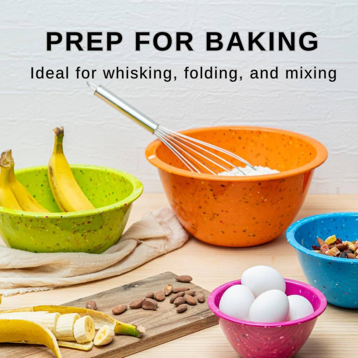 Confetti-speckled orange mixing bowl with whisk, with green and blue bowls nearby