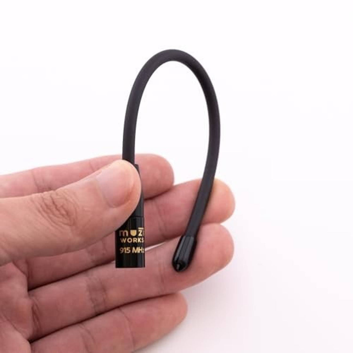 Black 915 MHz whip antenna held in hand, branded label on base