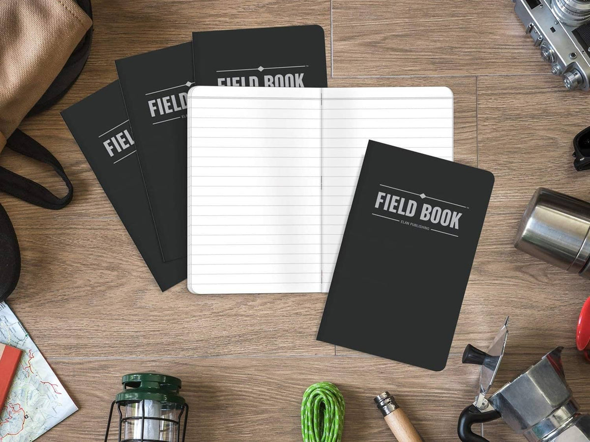 Black Field Book pocket notebooks with one open to lined pages, shown with accessories nearby