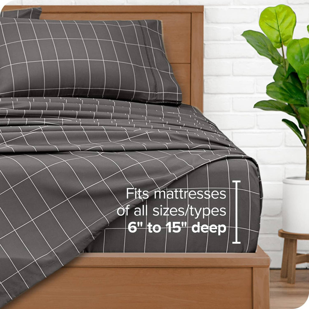 Grey fitted sheet and pillowcase with white grid lines, stacked on a bed