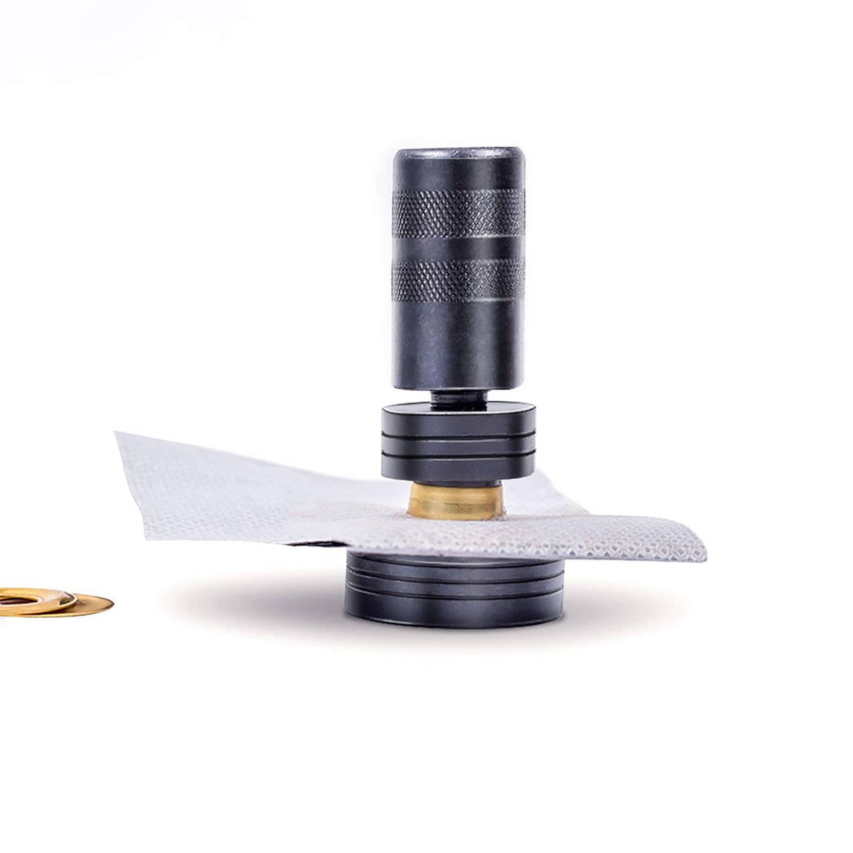 Punch tool pressing a solid brass grommet into fabric on a hard anvil block