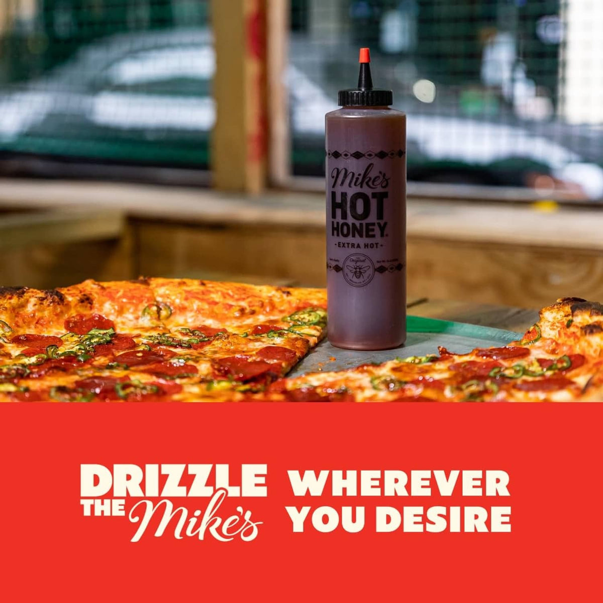 Extra hot honey squeeze bottle standing on a pizza tabletop