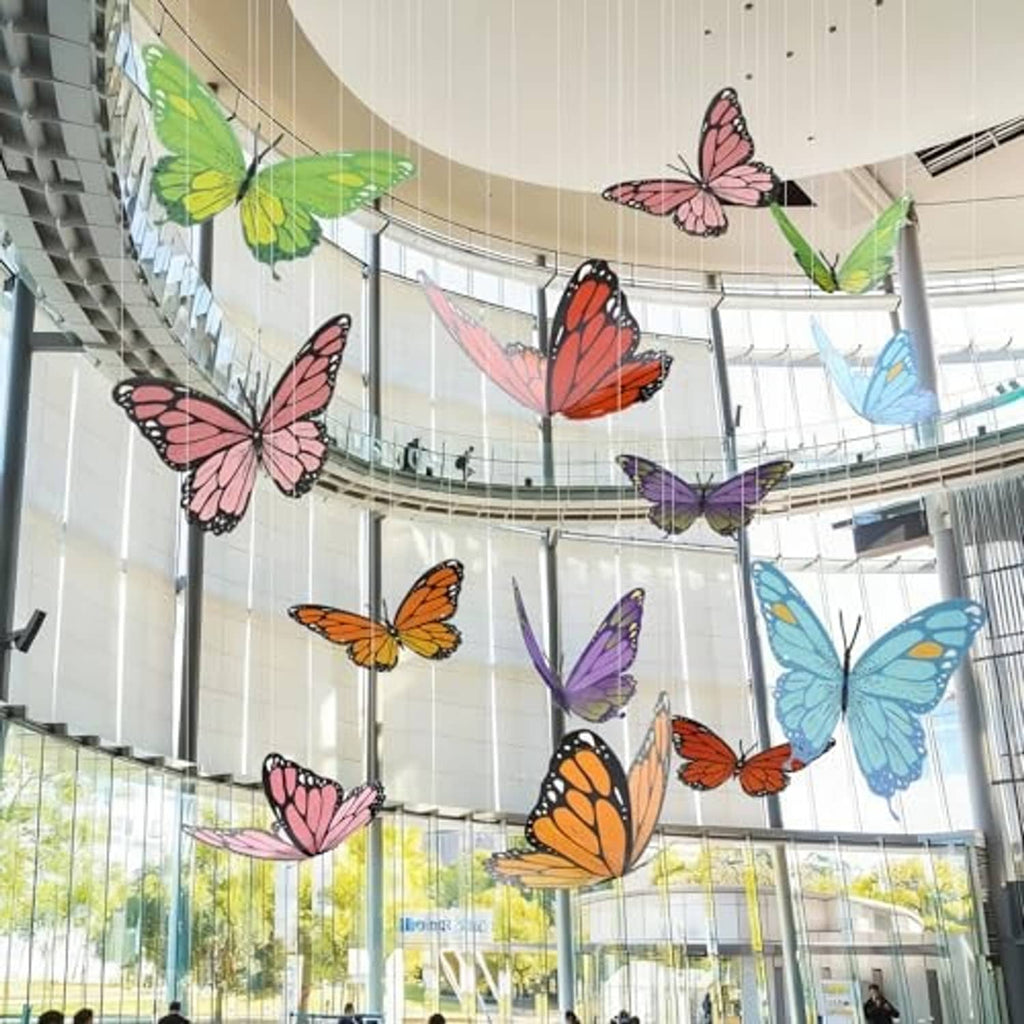 Large colorful 3D paper butterflies suspended from high ceiling atrium decor