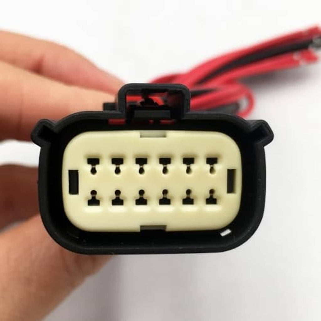 Close-up of 12-pin headlight connector plug socket with black housing and red wires