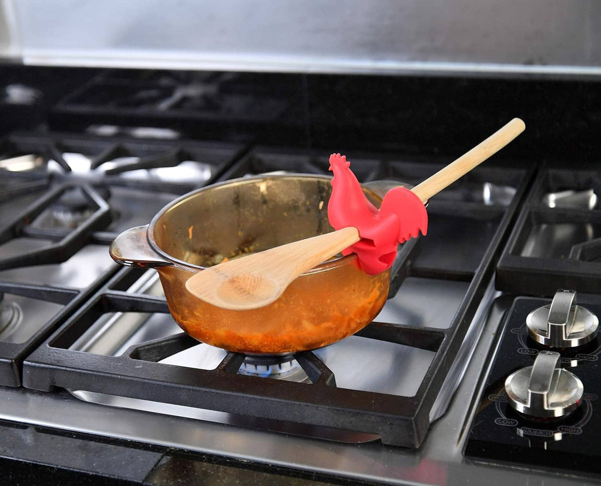 Red rooster spoon holder on skillet with wooden spatula across rim