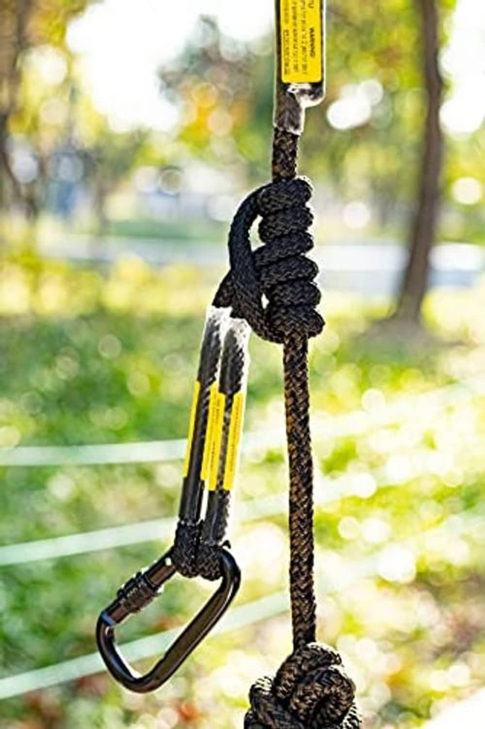 Treestand safety rope close-up on tree with carabiner and braided loop, yellow label
