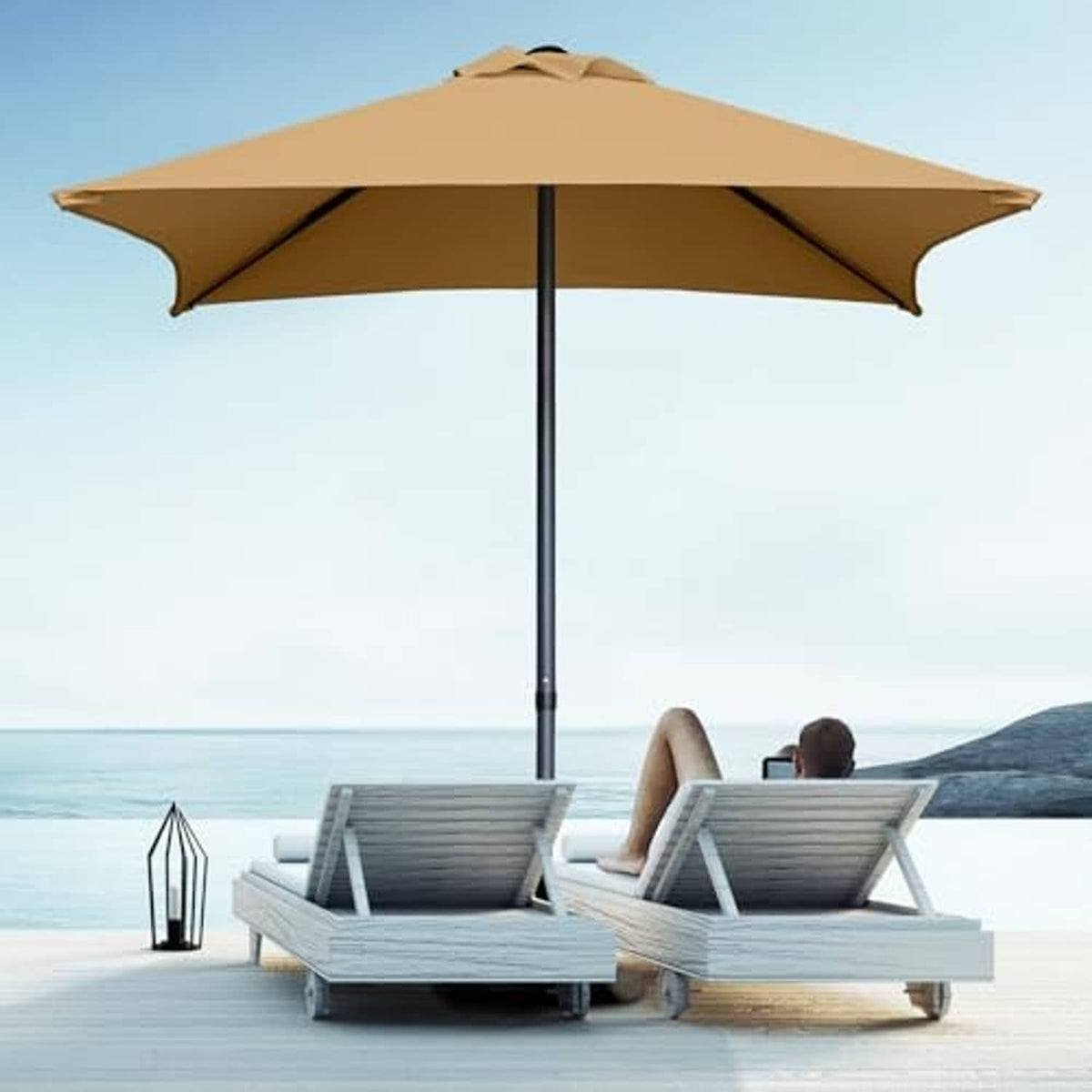 Tan mini square patio umbrella with tall black pole above outdoor lounge chairs