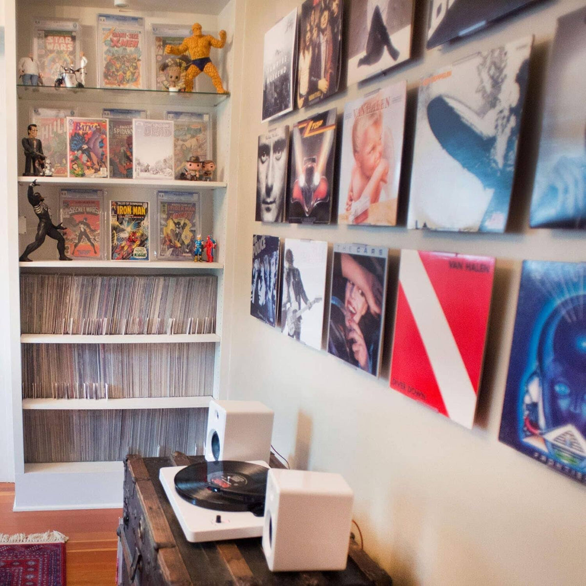 Wall display of multiple record covers on album display brackets and shelf