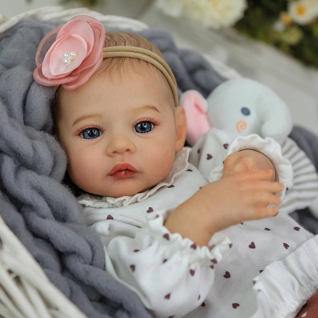 Realistic 18-inch reborn baby girl close-up with pink flower headband and plush bunny toy.