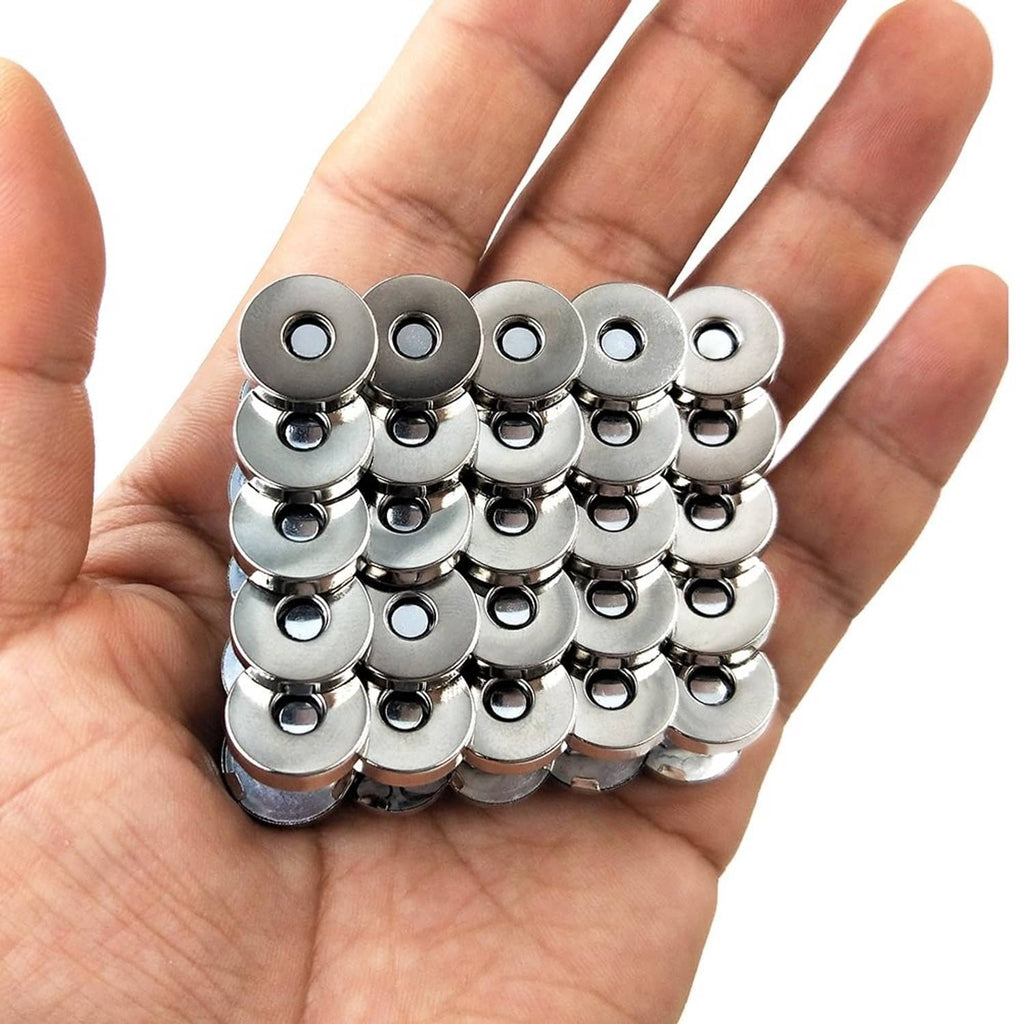 Silver-tone magnetic purse snap clasps held in hand, round metal bases and caps
