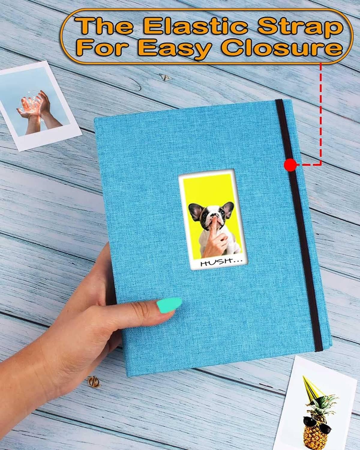 Blue mini photo album with elastic strap close-up; hand holds bound book on wood