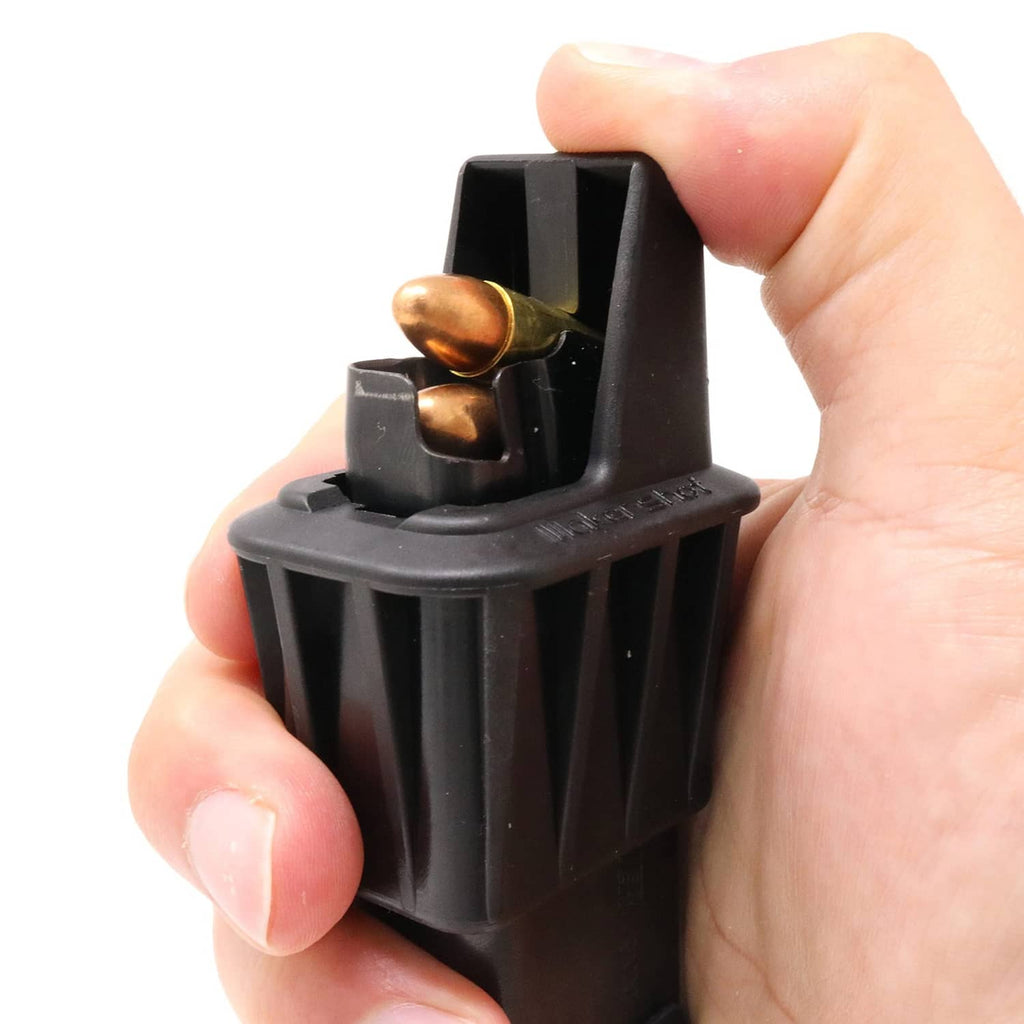 Hand holding black speed loader with brass rounds in the loading channel
