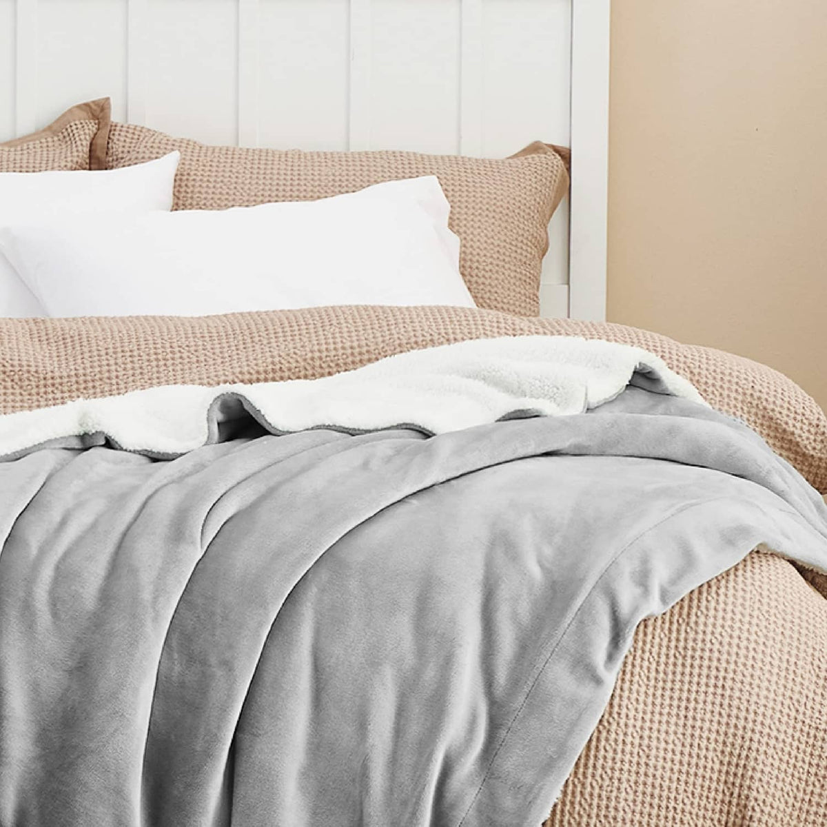 Light grey sherpa fleece throw blanket on bed with textured edge detail
