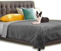 Gray waterproof bed cover draped over a bed with quilted mattress pad and pet dog