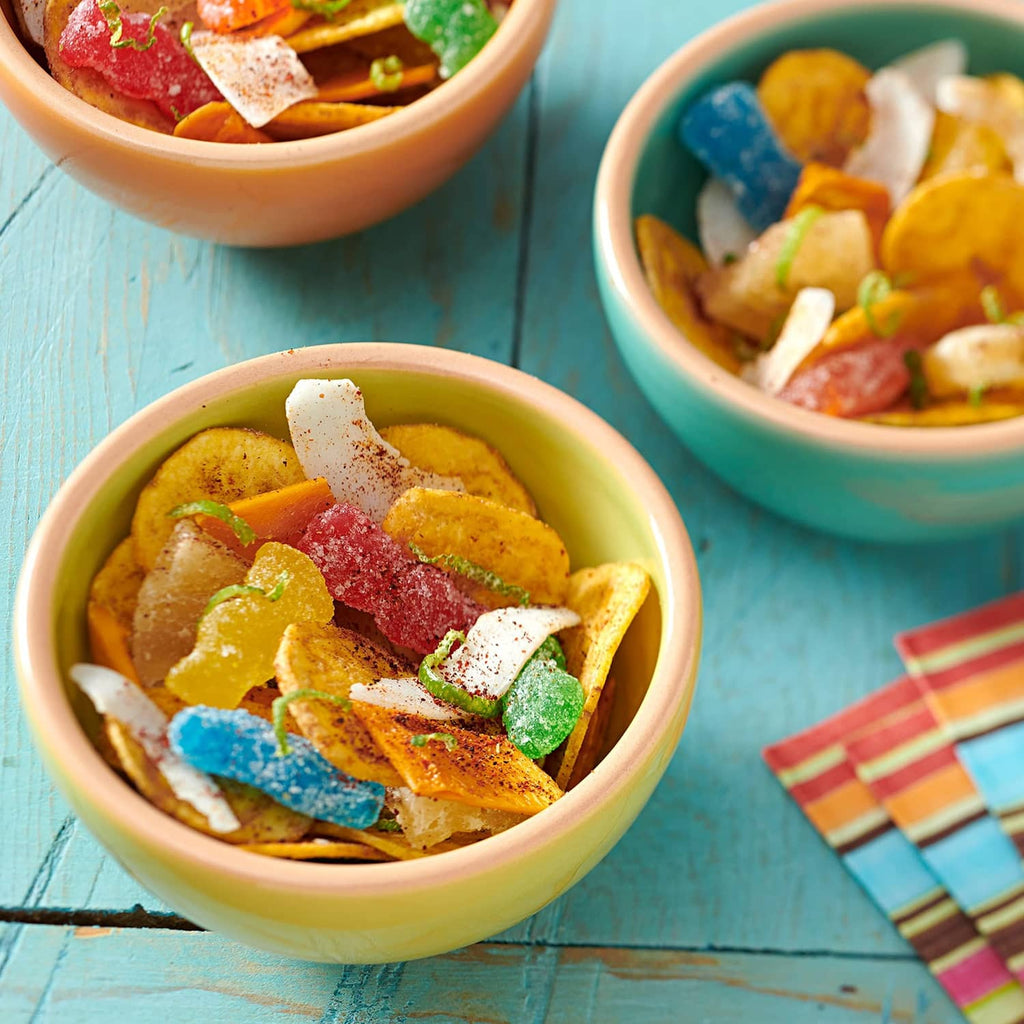 Bowl of assorted sour candy pieces on a blue table with another bowl nearby