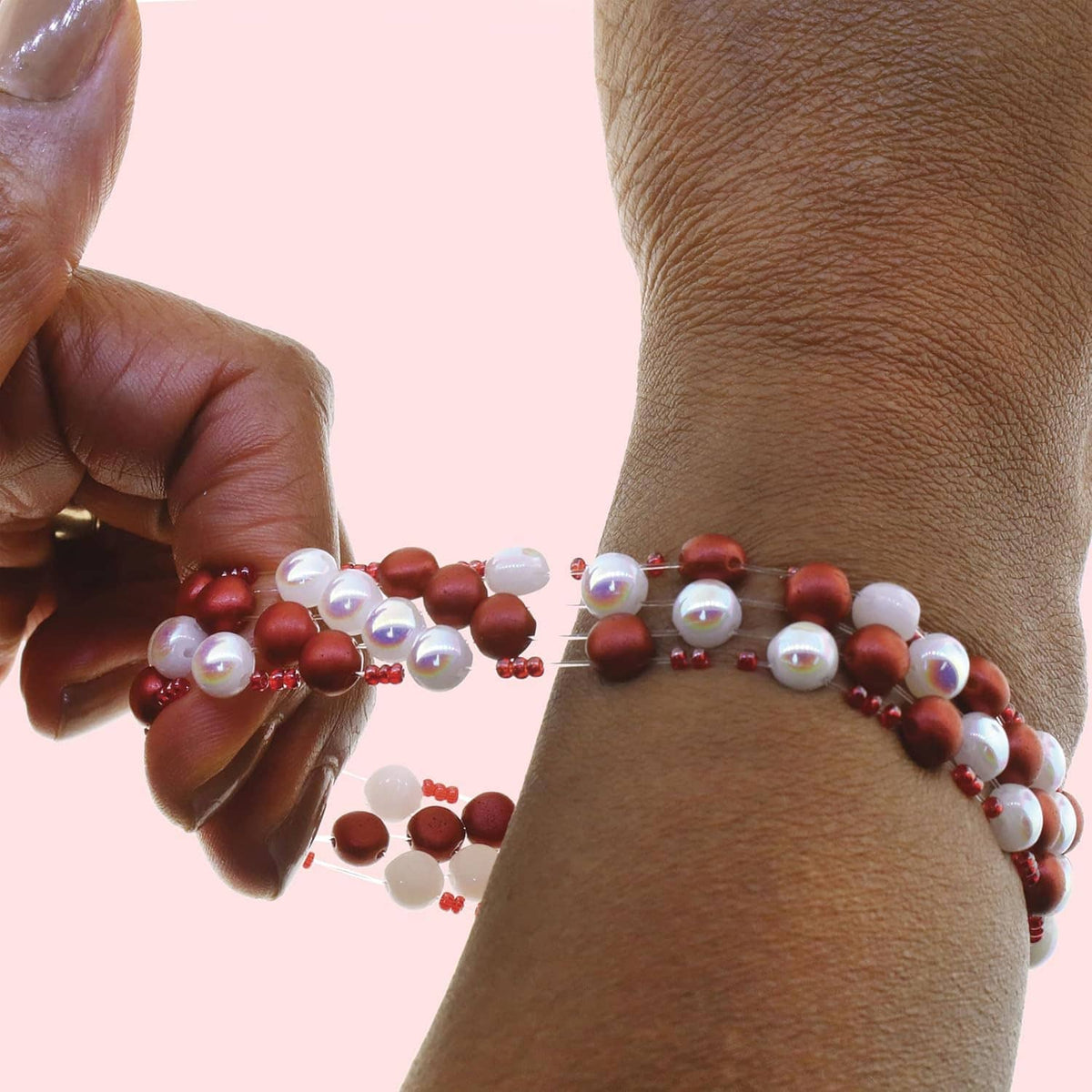 Elastic bead cord bracelet on wrist with clear cord and red bead accents