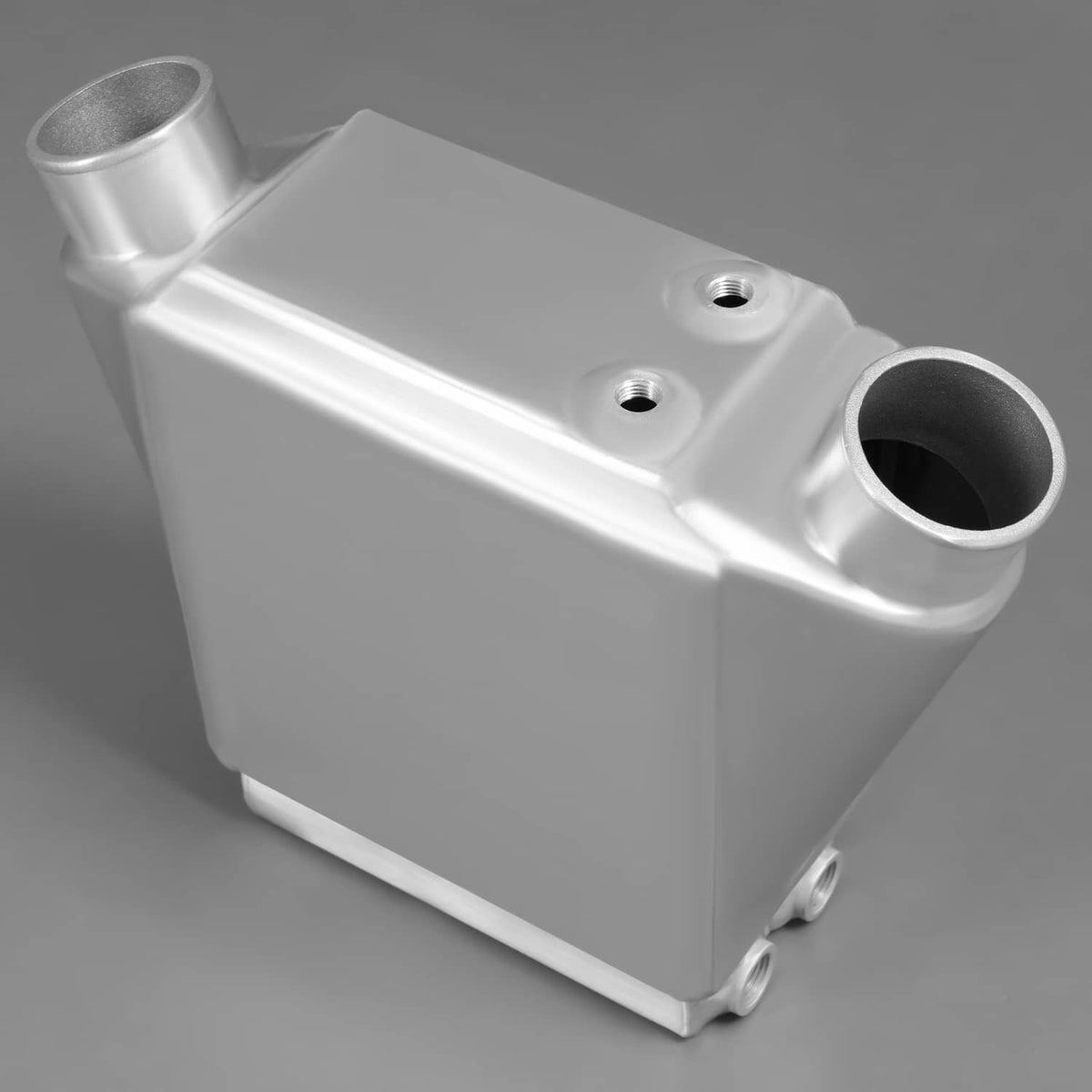 Aluminum intercooler with large circular inlet port and two top mounting holes.