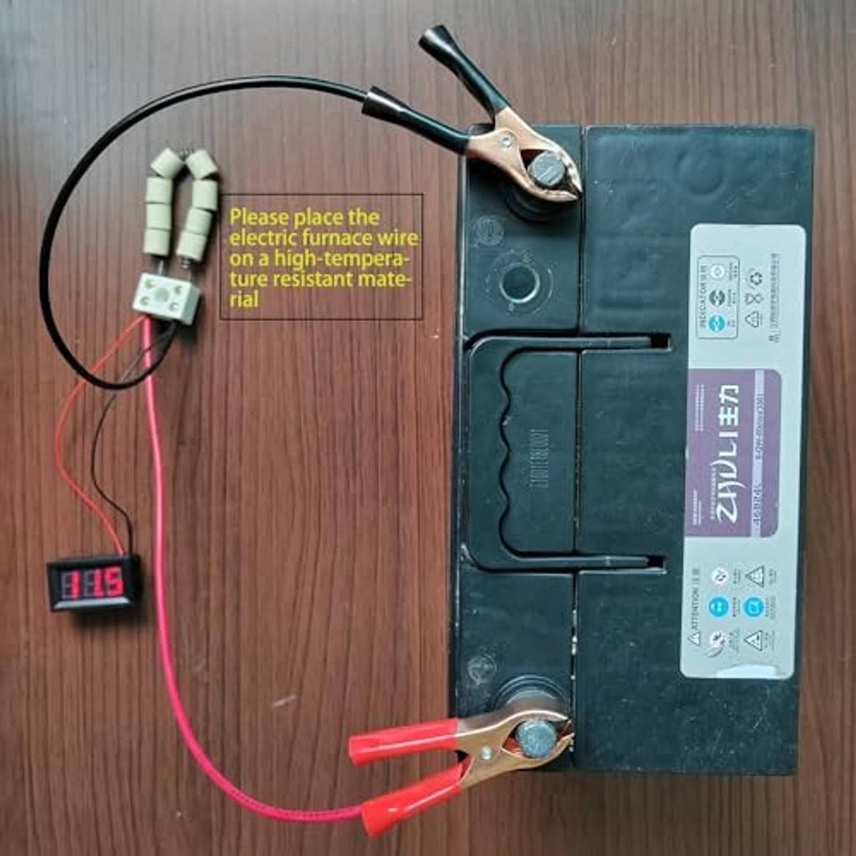 12V battery load tester connected to battery with alligator clips and small voltage display