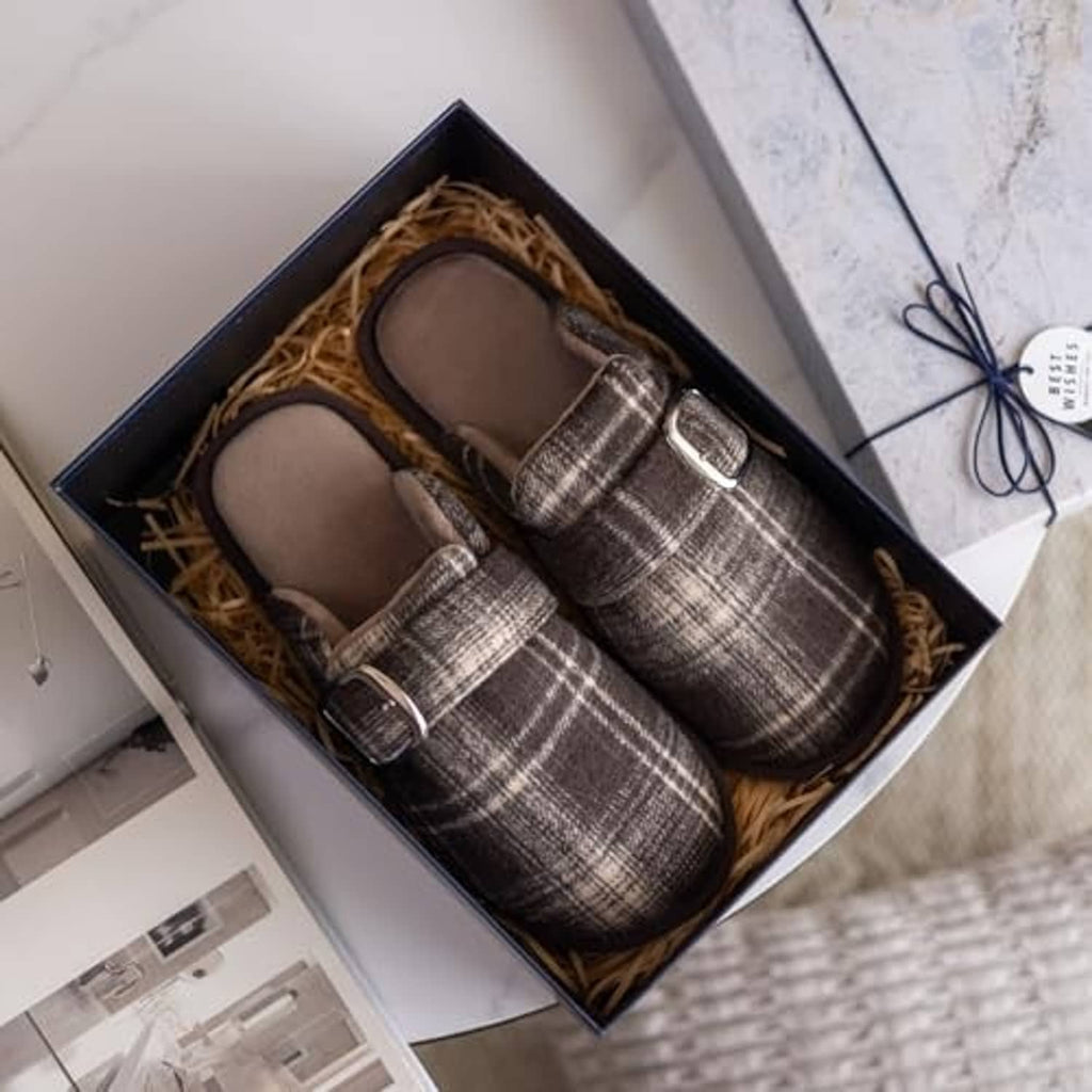 Pair of brown and beige plaid fuzzy slippers with buckle strap in gift box