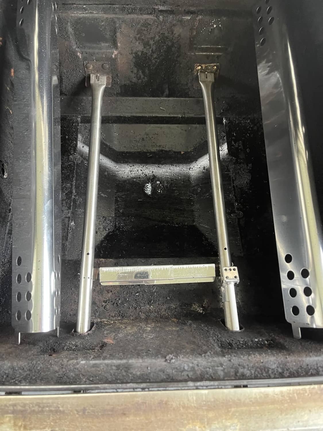 Stainless steel burner tube assembly installed inside a grill firebox