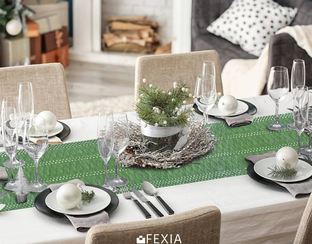 Green table runner with tassel fringe across dining table, textured woven surface.