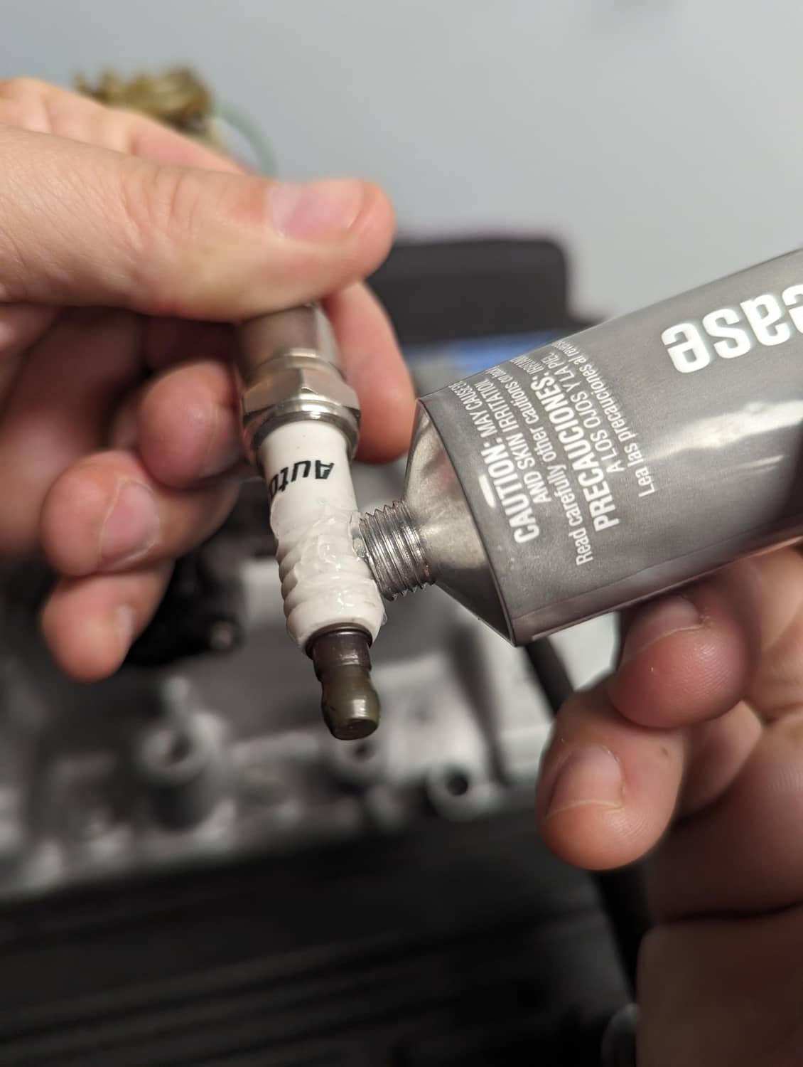 Dielectric Grease applied to spark plug threads with tube held in hand