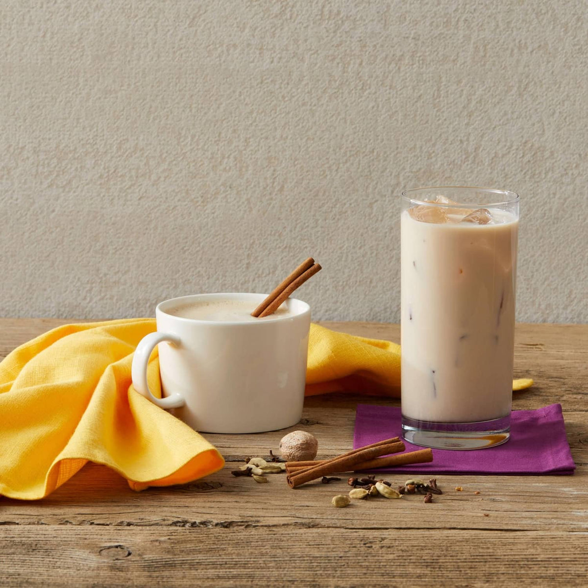 Chai latte made with Oregon Chai mix in two cups with cinnamon sticks and cloth