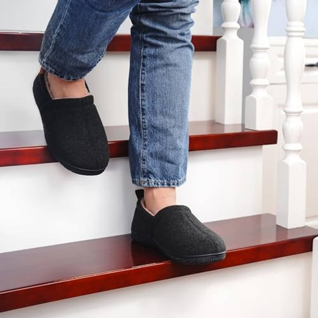 Black slip-on slippers on steps with thick cushioned sole and rear opening