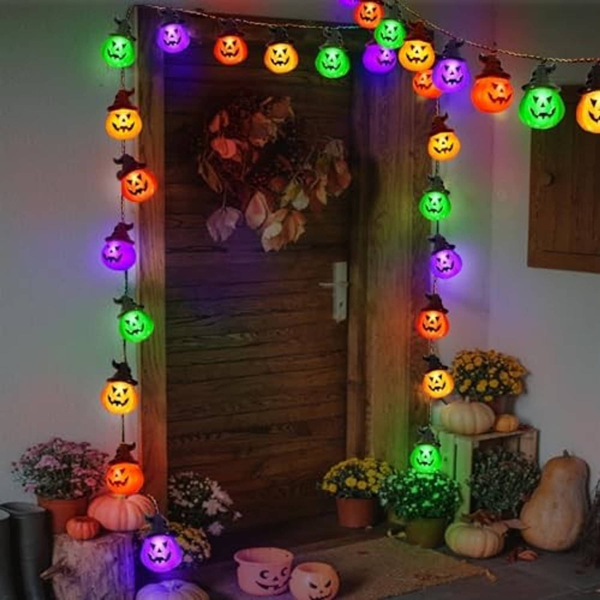Solar pumpkin string lights with multicolor glowing jack-o'-lantern bulbs hanging near a porch door.